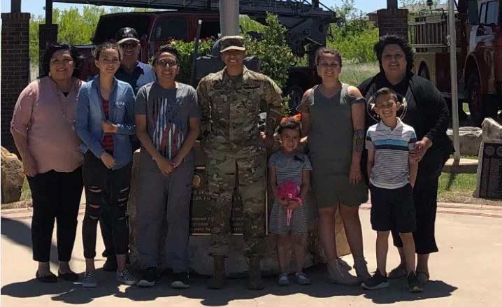 women in uniform surrounded by family