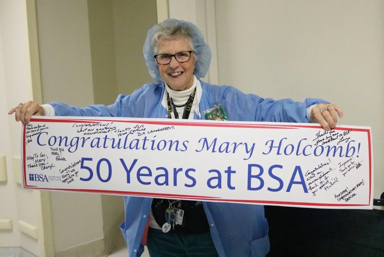 elderly woman holding up 50 years at BSA sign
